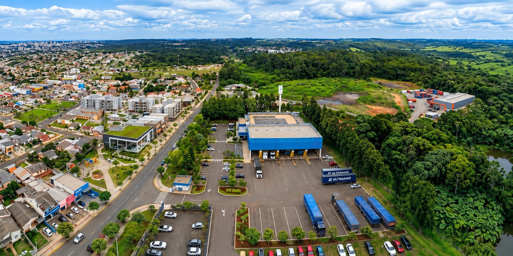 Vista aérea de um terminal logístico com carretas no pátio, entre a área urbana e a mata que cerca o terreno